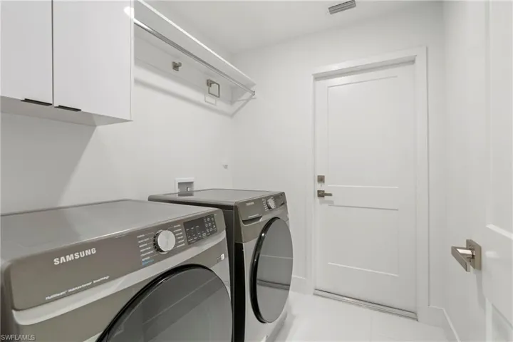 Laundry area with cabinets, light tile patterned flooring, and washing machine and clothes dryer