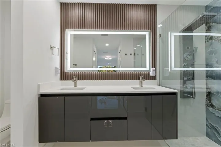 Bathroom featuring toilet, an enclosed shower, and vanity