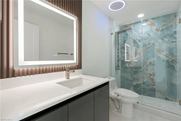 Bathroom featuring vanity, a shower with shower door, and toilet