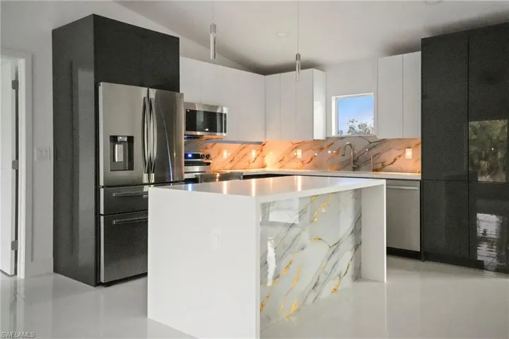Kitchen with white cabinetry, decorative backsplash, a kitchen island, and appliances with stainless steel finishes