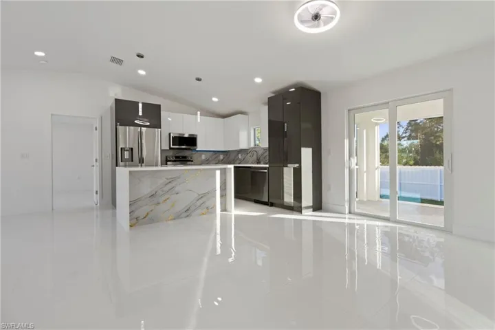 Kitchen featuring hanging light fixtures, stainless steel appliances, vaulted ceiling, decorative backsplash, and a kitchen island