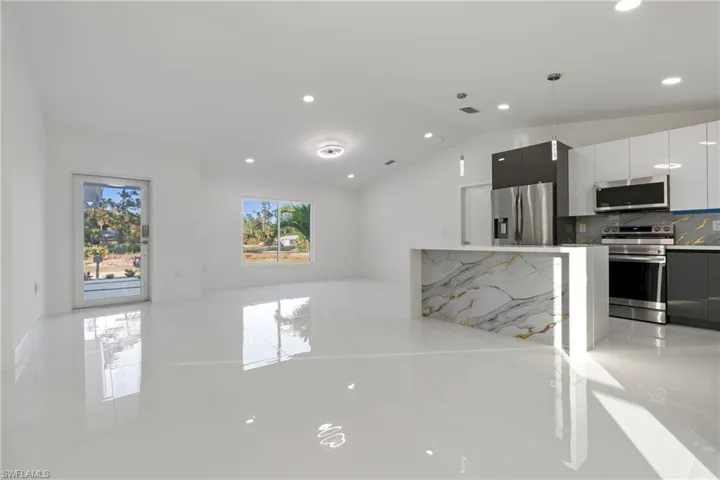 Kitchen featuring pendant lighting, stainless steel appliances, white cabinetry, and a wealth of natural light