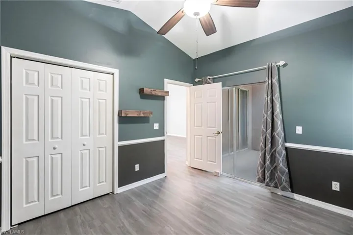 Unfurnished bedroom featuring ceiling fan, high vaulted ceiling, hardwood / wood-style flooring, and a closet