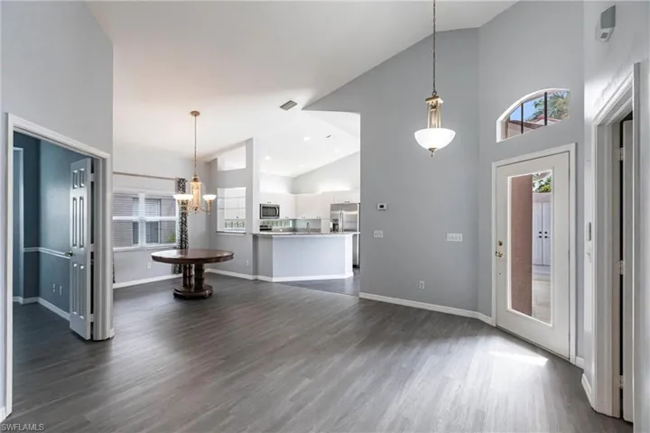 Unfurnished living room featuring high vaulted ceiling, dark hardwood / wood-style floors, and a chandelier