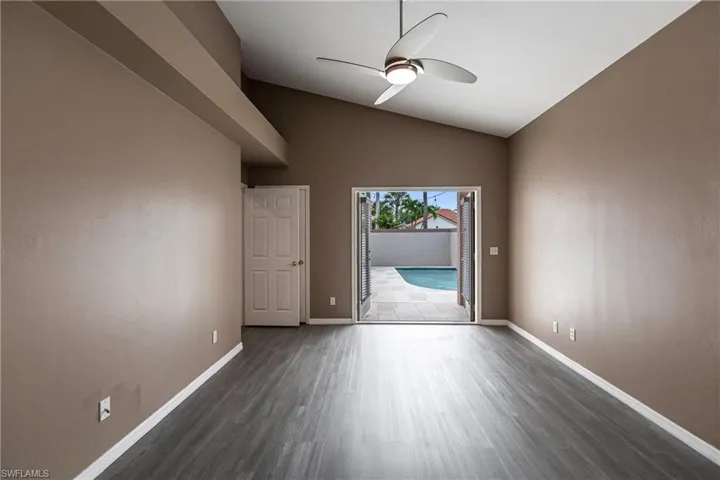 Unfurnished room with ceiling fan, vaulted ceiling, and dark hardwood / wood-style flooring
