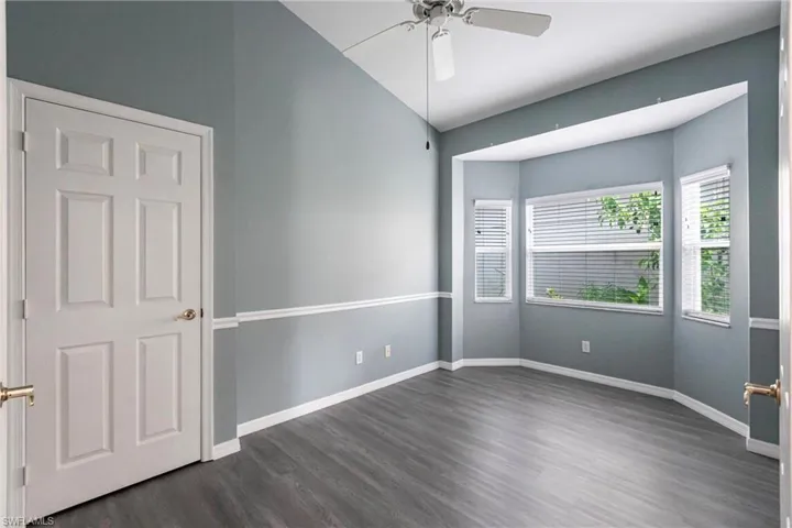 Spare room with ceiling fan, dark wood-type flooring, and lofted ceiling