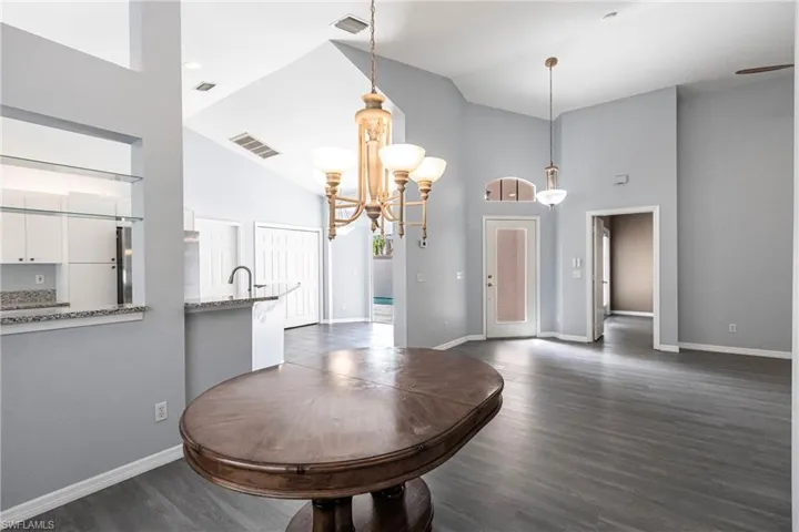 Dining space with high vaulted ceiling, dark hardwood / wood-style flooring, and a chandelier