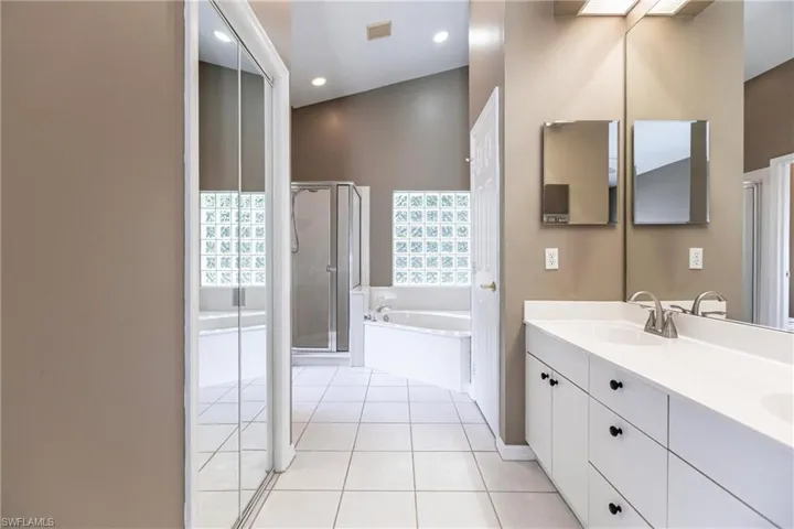 Bathroom with double sink vanity, high vaulted ceiling, tile patterned flooring, and separate shower and tub