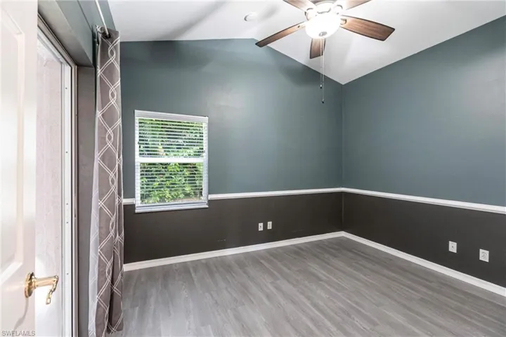 Spare room featuring ceiling fan, lofted ceiling, and wood-type flooring