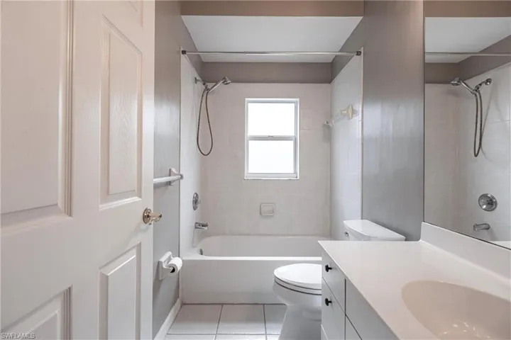 Full bathroom featuring tiled shower / bath combo, vanity, tile patterned flooring, and toilet