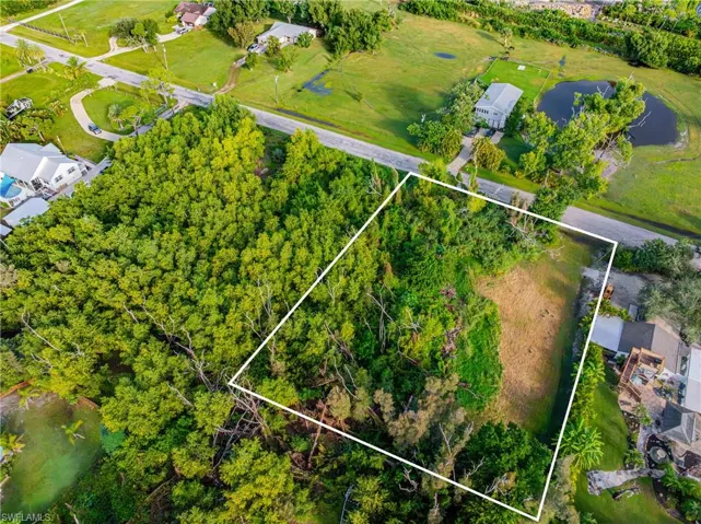 Aerial view of property and surrounding area with a tree filled landscape and property parcel outlined