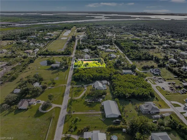 Aerial view of property's location featuring a large body of water, property parcel outlined, and nearby suburban area