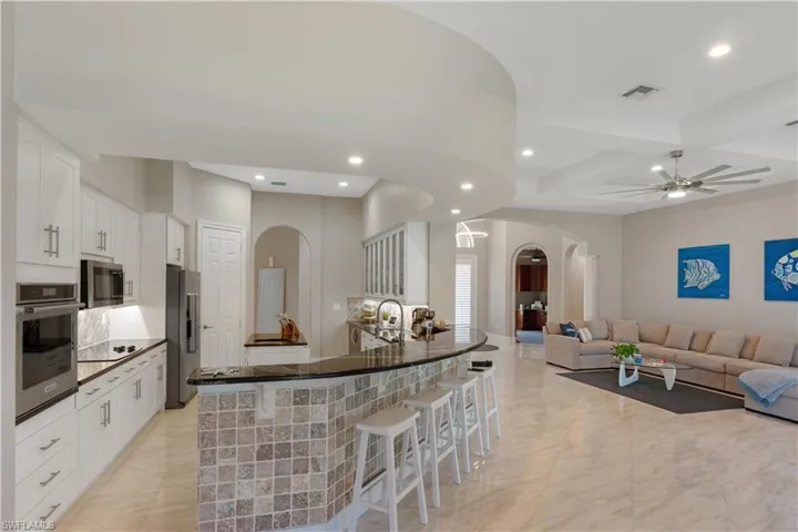 Kitchen with white cabinetry, a kitchen bar, kitchen peninsula, ceiling fan, and appliances with stainless steel finishes