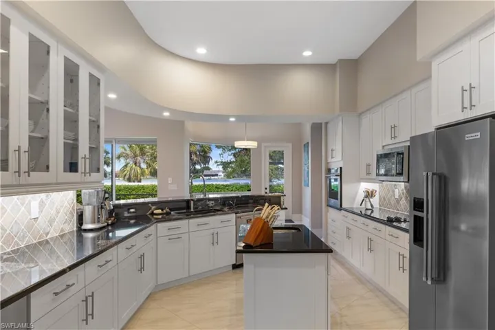 Kitchen with backsplash, a kitchen island, stainless steel appliances, and sink