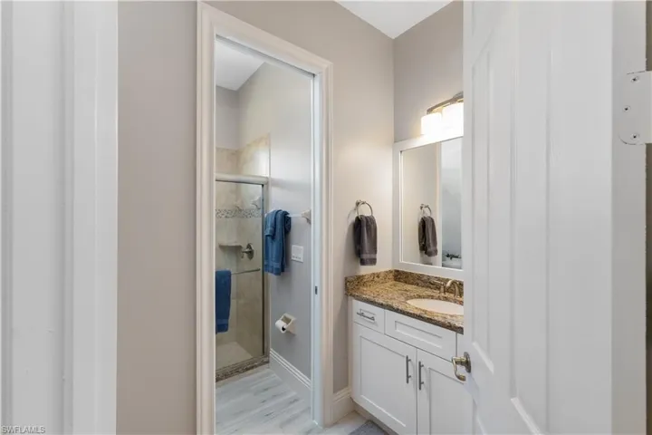 Bathroom featuring vanity, light ceramic tile flooring, and an enclosed shower