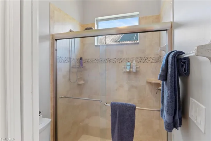 Bathroom featuring toilet and an enclosed shower with premium tile and sliding glass shower door