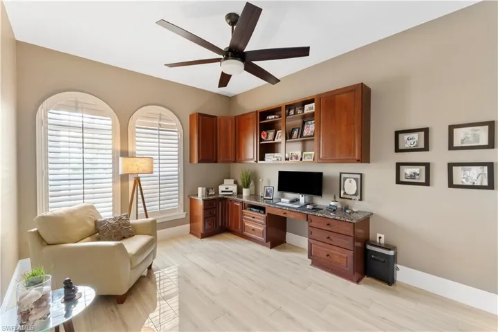 Office with built in desk, custom granite counter top,  light ceramic tile flooring and ceiling fan