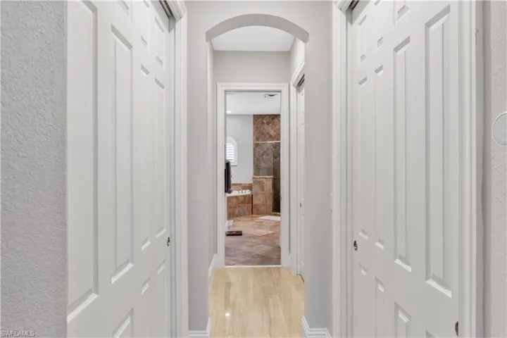 Corridor to owners bath featuring light ceramic tile flooring