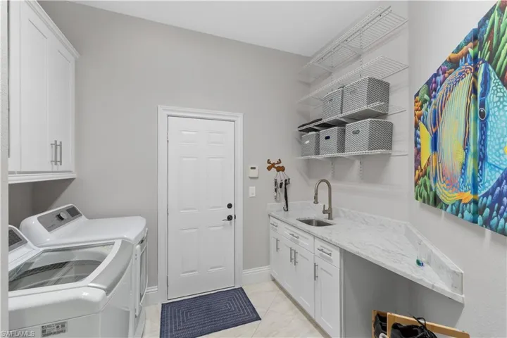 laundry room with marble countertop, tile floors, cabinets, washing machine and dryer, and sink