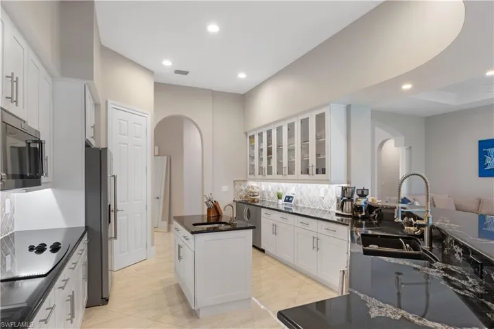 Gourmet kitchen featuring a kitchen island, sink, appliances with stainless steel finishes, and white cabinetry