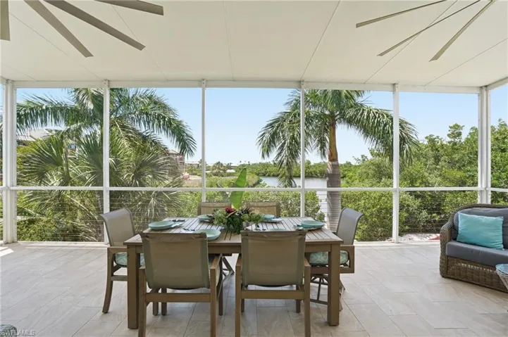 Screened outdoor living area with light-toned tile flooring, white frame enclosure, and a ceiling-mounted fan - Virtually Edited Image