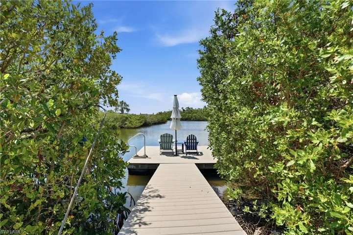 Waterfront property featuring a composite wood dock, natural waterway access, and lush surrounding foliage - Virtually Edited Image