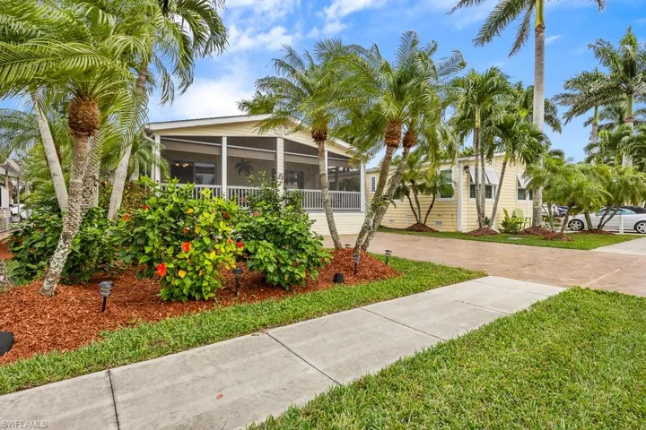 View of property's community featuring a sunroom, driveway, and a yard