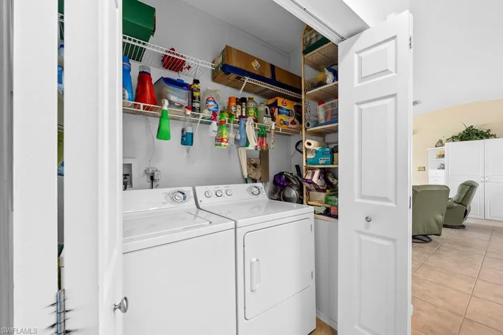 Laundry room featuring light tile patterned floors and washing machine and clothes dryer