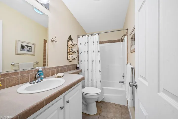 Bathroom with shower / tub combo, vanity, light tile patterned floors, and decorative backsplash