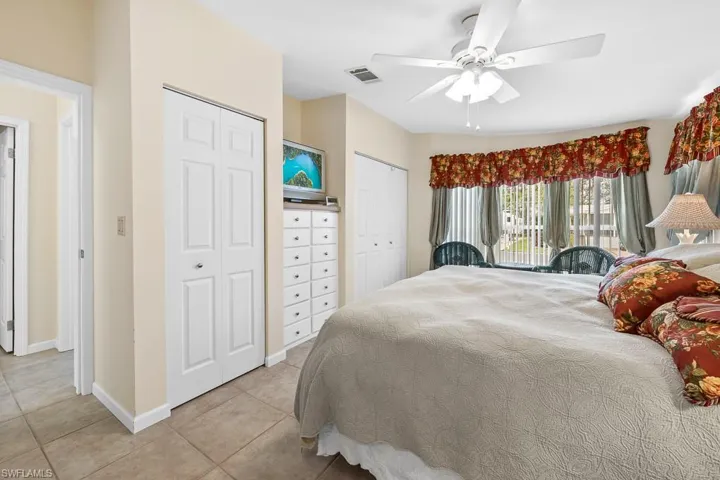 Bedroom featuring two closets, light tile patterned floors, and a ceiling fan