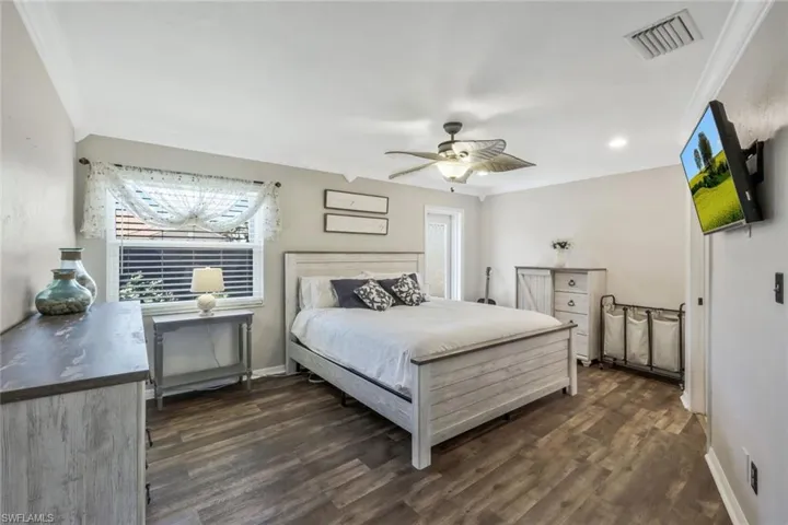 Bedroom with dark hardwood / wood-style flooring, ornamental molding, and ceiling fan