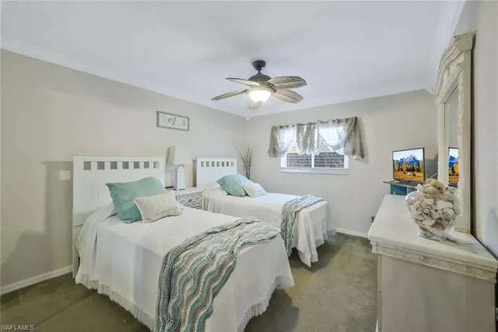 Carpeted bedroom with crown molding and ceiling fan