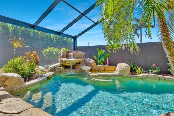 View of pool with pool water feature and screen enclosure