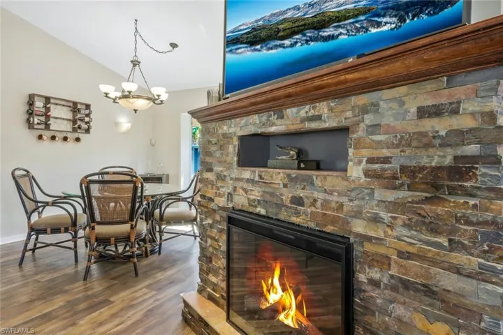 Dining area featuring lofted ceiling, a stone fireplace, and hardwood / wood-style floors