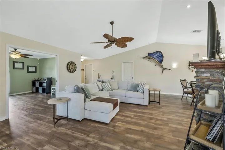 Living room featuring dark hardwood / wood-style flooring, lofted ceiling, and ceiling fan