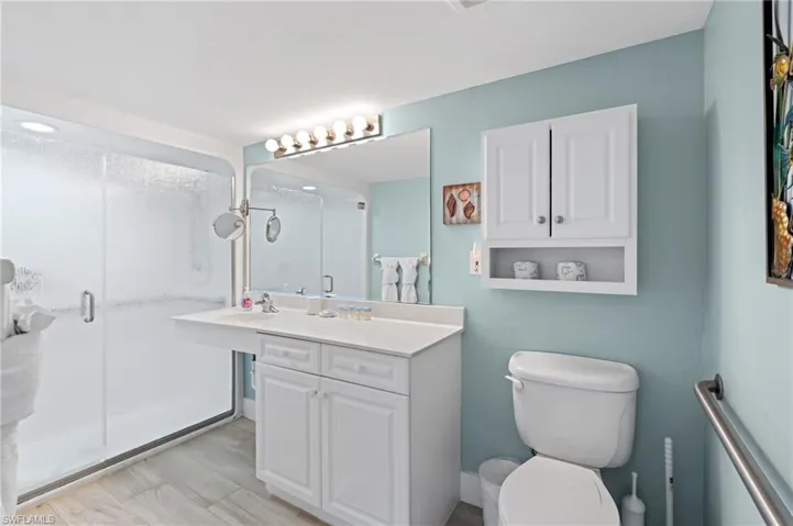 Bathroom featuring toilet, vanity, and a stall shower