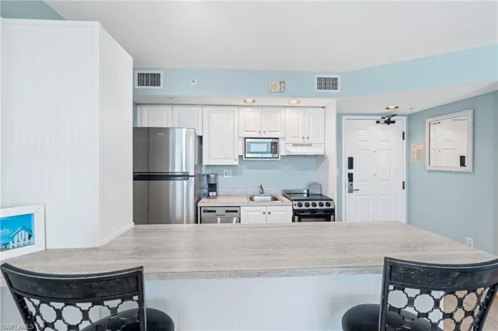 Kitchen with visible vents, appliances with stainless steel finishes, a breakfast bar area, and a sink