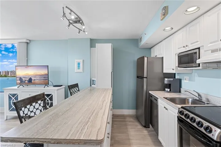 Kitchen featuring white cabinets, light wood-type flooring, stainless steel appliances, and a sink