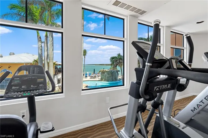 Workout area featuring carpet, baseboards, visible vents, and a water view
