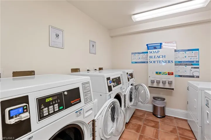 Community laundry room featuring washing machine and dryer, baseboards, and light tile patterned flooring