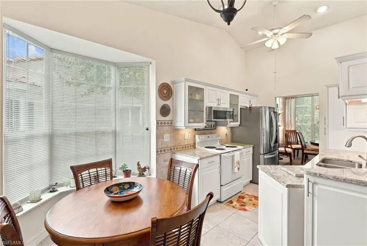 Kitchen featuring white cabinetry, stainless steel appliances, a tiled backsplash, and granite countertops