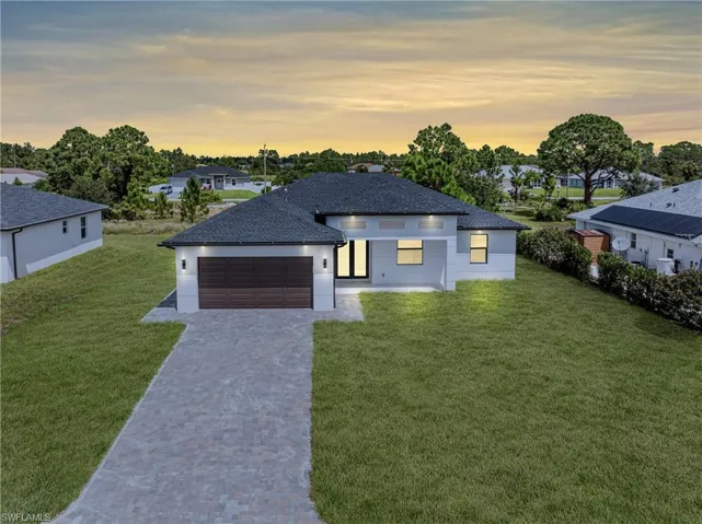 View of front of property featuring a yard and a garage