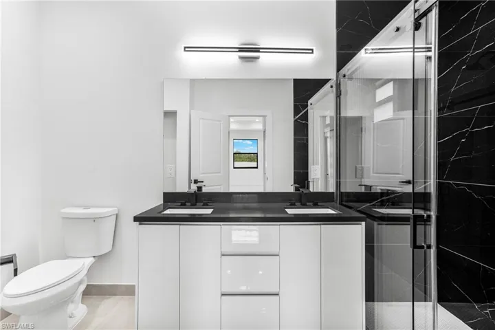 Bathroom featuring vanity, toilet, and an enclosed shower