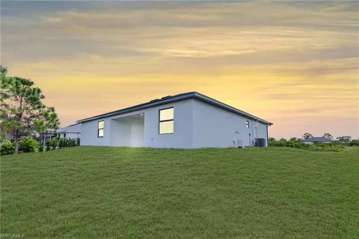 Property exterior at dusk featuring a yard and central AC