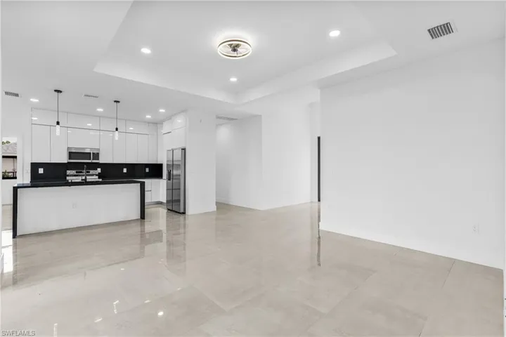 Kitchen with pendant lighting, backsplash, a tray ceiling, stainless steel appliances, and white cabinets