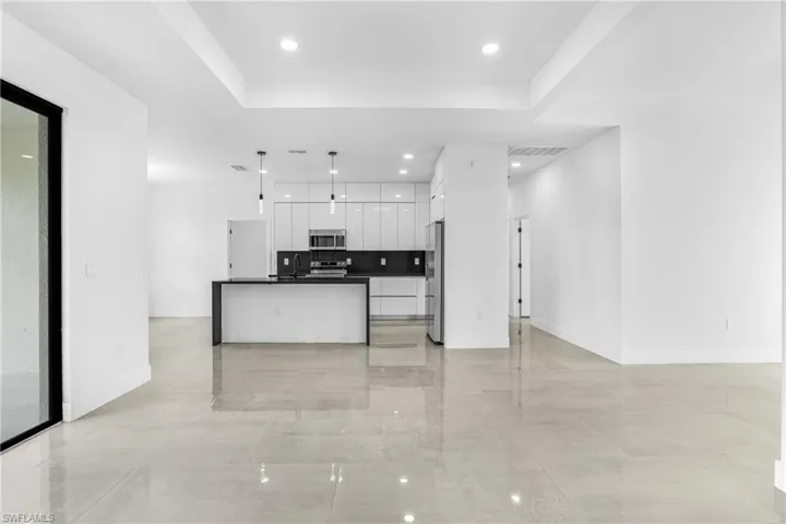 Kitchen featuring backsplash, stainless steel appliances, decorative light fixtures, sink, and white cabinets