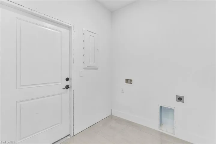 Washroom with hookup for a washing machine, light tile patterned floors, hookup for an electric dryer, and electric panel