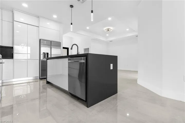 Kitchen featuring appliances with stainless steel finishes, a raised ceiling, white cabinets, and hanging light fixtures