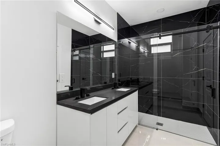 Bathroom with vanity, toilet, a healthy amount of sunlight, and walk in shower