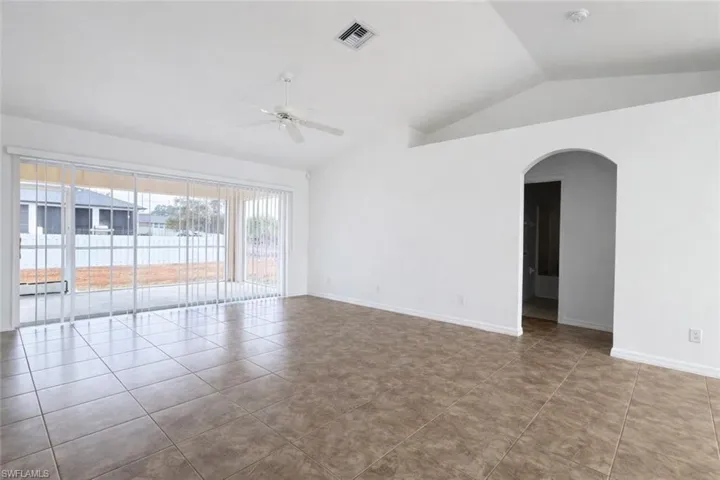 Spare room featuring a ceiling fan, arched walkways, and tile patterned flooring